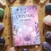The Crystal Journal laying on a wooden table, beautifully styled and surrounded by healing crystals like amethyst, rose quartz, and lavender sprigs.