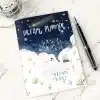 The Dream Planner with a whimsical celestial cover design, resting on a marble desk next to a fountain pen.