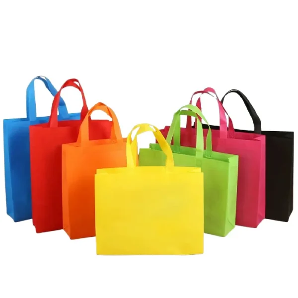 A lineup of colorful reusable non-woven shopping bags in black, green, blue, pink, red, and orange.