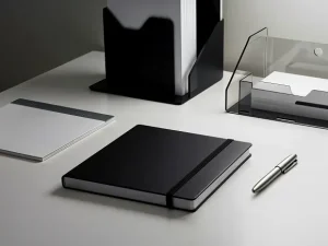 Modern office space with a neatly arranged employee welcome kit on a desk, featuring a branded notebook, pen, and a sleek custom box