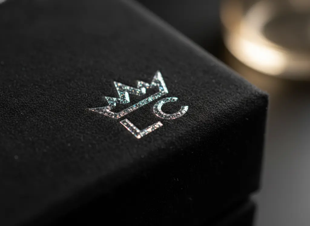 Close-up of a luxury black box with a glossy Spot UV logo reflecting light against a matte background