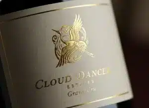 FEATURED A close-up, high-resolution shot of a premium wine bottle featuring a Cloud Dancer soft white textured label with intricate gold foil embossing. The lighting highlights the tactile grain of the paper .webp
